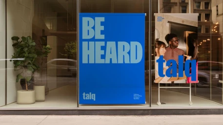TALQ brand identity display on large blue posters in a glass storefront window