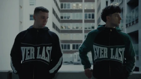 Two men wearing branded Everlast hoodies standing outdoors against a residential building exterior background.
