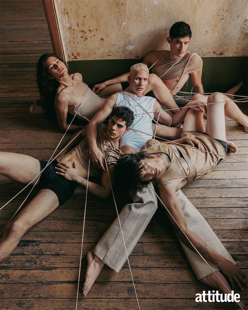 High-angle shot of five young adult men with tan and brown skin tones, in an old interior. Men are partially clothed and connected by string.