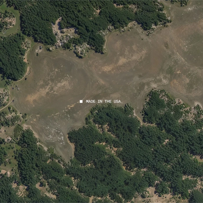 Aerial view of a landscape with dense green forests and barren earth surrounding a central body of water.