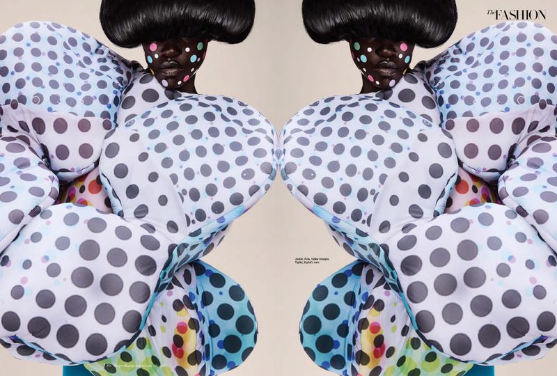 Two identical fashion models with dark skin, sculptural black wigs, and polka-dot bodysuits posing against a neutral backdrop.
