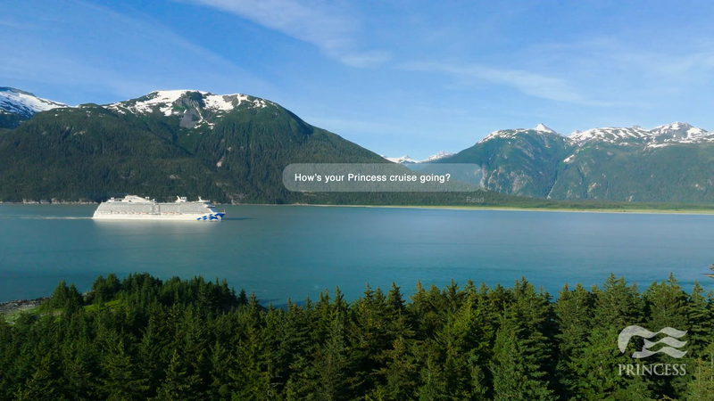 Cruise ship sails on blue water near forested mountains under a clear sky, showcasing nature and travel.
