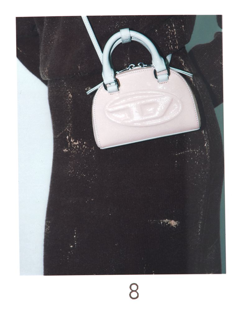 Fashion shoot featuring a light purple Diesel purse with a prominent logo, displayed against a blurred textured brown dress.