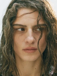 Close-up portrait of a model with wet wavy dark hair and natural skin tones looking away from the camera.