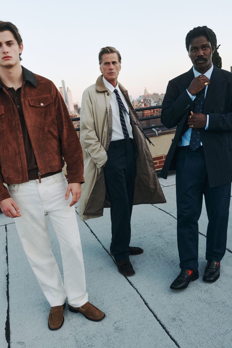 Three men on a rooftop wearing fashionable jackets and coats. The urban skyline in the background adds depth to the outdoor fashion shot.