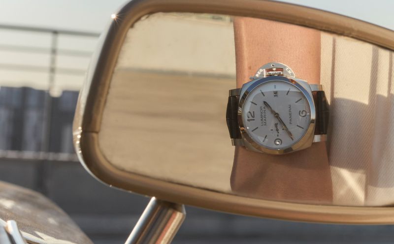 Wristwatch reflection on a motorcycle mirror. The face of the timepiece features an elegant design with distinct markers.
