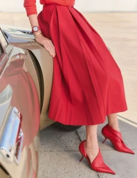 Model wearing a red skirt and red heels leaning against a car in Madame Figaro editorial
