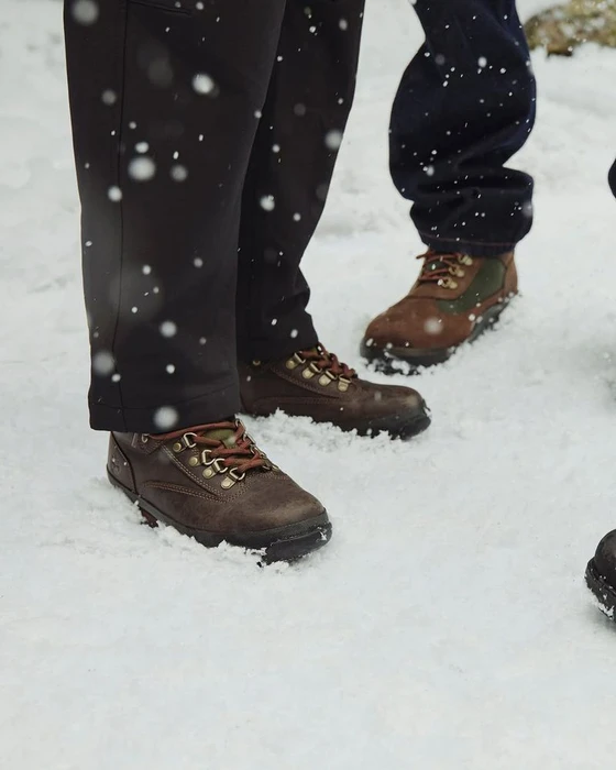 Close-up of people wearing leather boots standing in deep snow during a winter snowfall