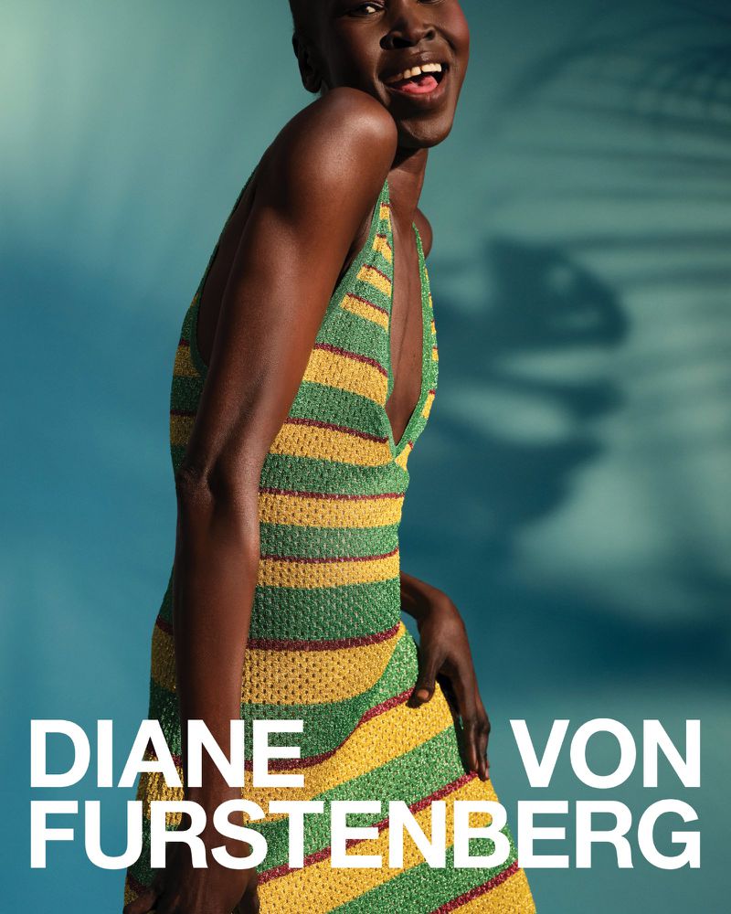 Dark-skinned model wears a striped knit dress by Diane von Furstenberg, smiling against a teal background with tree shadows in studio lighting.