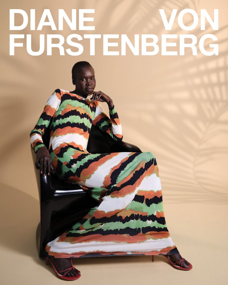 Elegant woman poses in a patterned maxi dress while seated in a black chair, with 'DIANE VON FURSTENBERG' text overlay and leaf shadows.