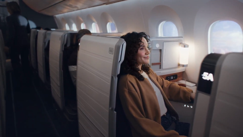 Woman enjoys premium airplane travel in comfort. Interior view of an airplane cabin with comfortable seating and a relaxed atmosphere.