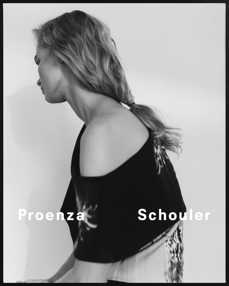 Black-and-white fashion portrait of a blonde woman in a top by Proenza Schouler, with a white backdrop and minimalist studio lighting.