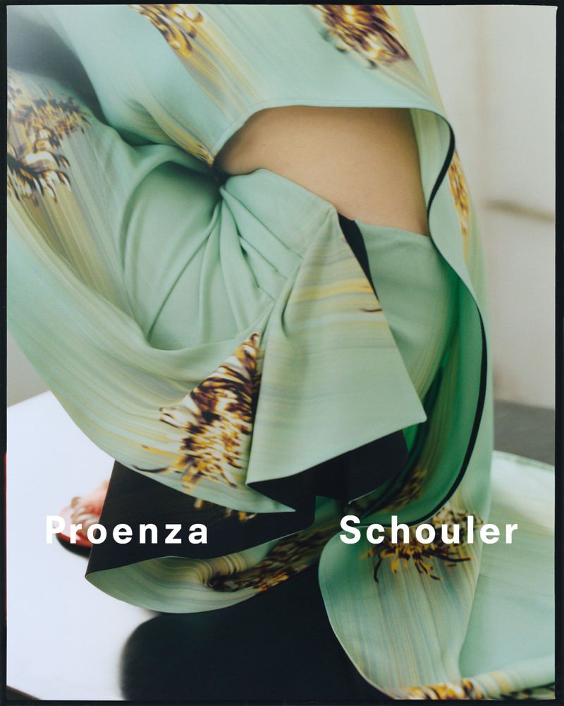 Close-up fashion shot of person wearing a light green garment with a flower pattern, showcasing Proenza Schouler brand logo.