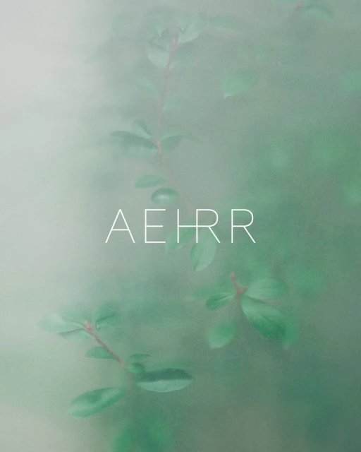 Green foliage with red stems is blurred with atmospheric fog. The text “AEHRR” is superimposed in white in the lower center.