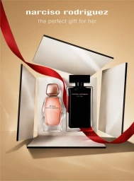 Two Narciso Rodriguez perfume bottles displayed inside an open white box with a looping red ribbon against a warm beige background.
