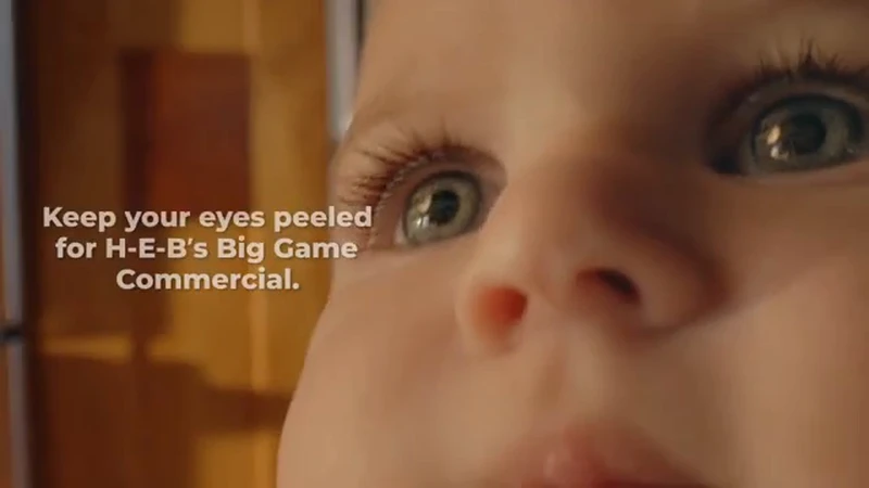 Close-up of an infant's face with striking blue eyes looking upward, alongside advertising text for a commercial game event.