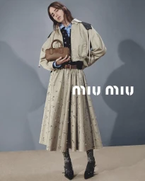 Model Taleedah Tamer holding a brown handbag wearing a beige skirt and jacket for Miu Miu Ramadan 2026