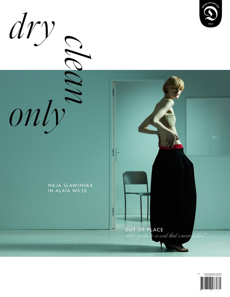 Magazine cover featuring a woman in fashionable attire, posing against a pale blue wall, with minimalist styling and clear typography.