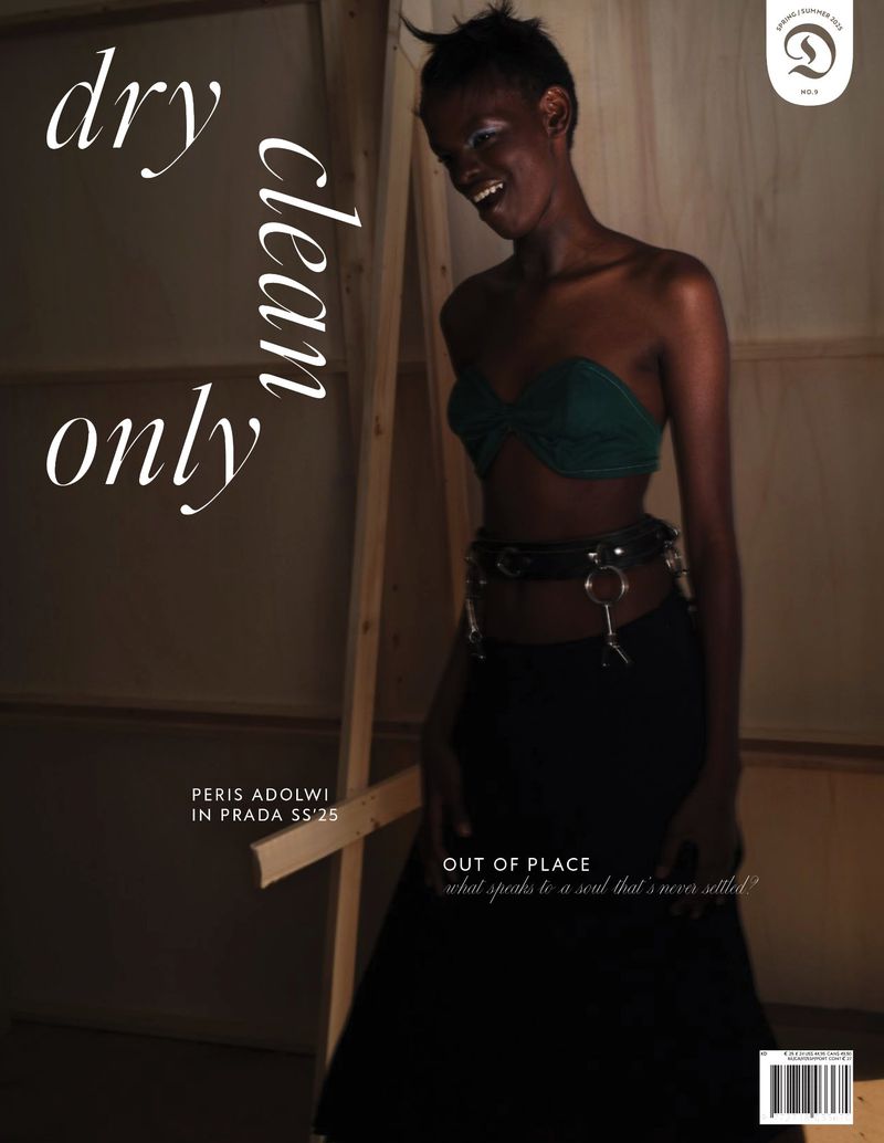 A fashion magazine cover featuring a Black woman wearing a green tube top and a long black skirt in a muted indoor setting.