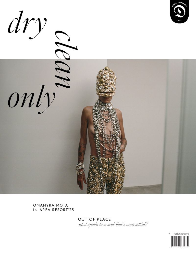 Editorial shot of a person in heavily beaded attire and headpiece, posing in a minimal room. 'Dry clean only' text overlay.