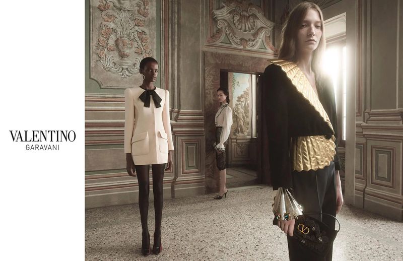Valentino Garavani fashion campaign featuring three women in a hall with neutral colors, ornate details, and soft, diffused lighting.
