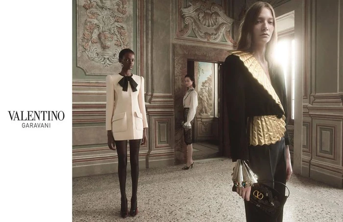 Models in tailored Valentino luxury fashion posing inside a classic European hall with ornate architectural wall panels