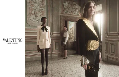 Models in tailored Valentino luxury fashion posing inside a classic European hall with ornate architectural wall panels