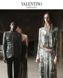 Models in high fashion clothing including a metallic sequin dress and tailored suit inside a grand room for Valentino S/S 2026