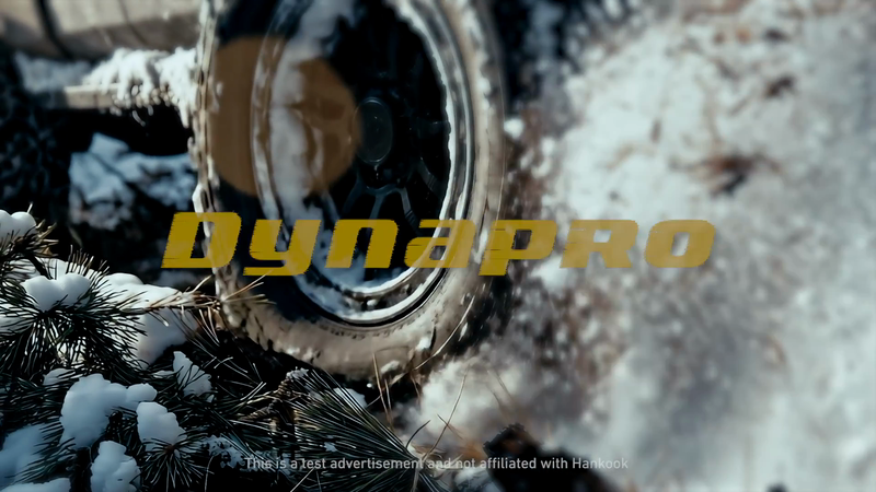 Truck tire covered in snow with the brand name Dynapro displayed in yellow letters over the tire in an outdoor winter setting.