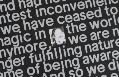 Close-up typography design featuring bold white text on a black background surrounding a small black-and-white portrait inset