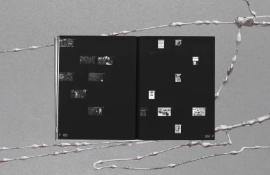 Open book layout with black pages and small thumbnails set against a textured grey background with organic metallic tendrils.