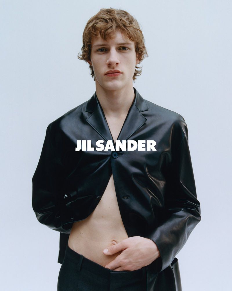 Model wearing a black leather blazer with open front against a plain white studio background.
