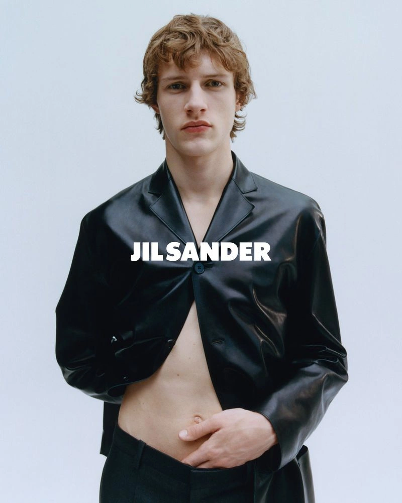 Model wearing a black leather blazer with open front against a plain white studio background.