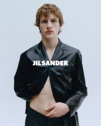 Model wearing a black leather blazer with open front against a plain white studio background.