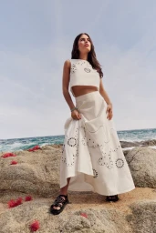 Model Lily Jean Harvey posing on rocky coast wearing white embroidered two piece outfit by photographer Berta Pfirsich.
