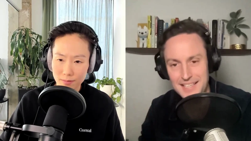 Two people are in a split-screen video call; one is a smiling man with headphones, and the other is a person with short hair and a microphone.