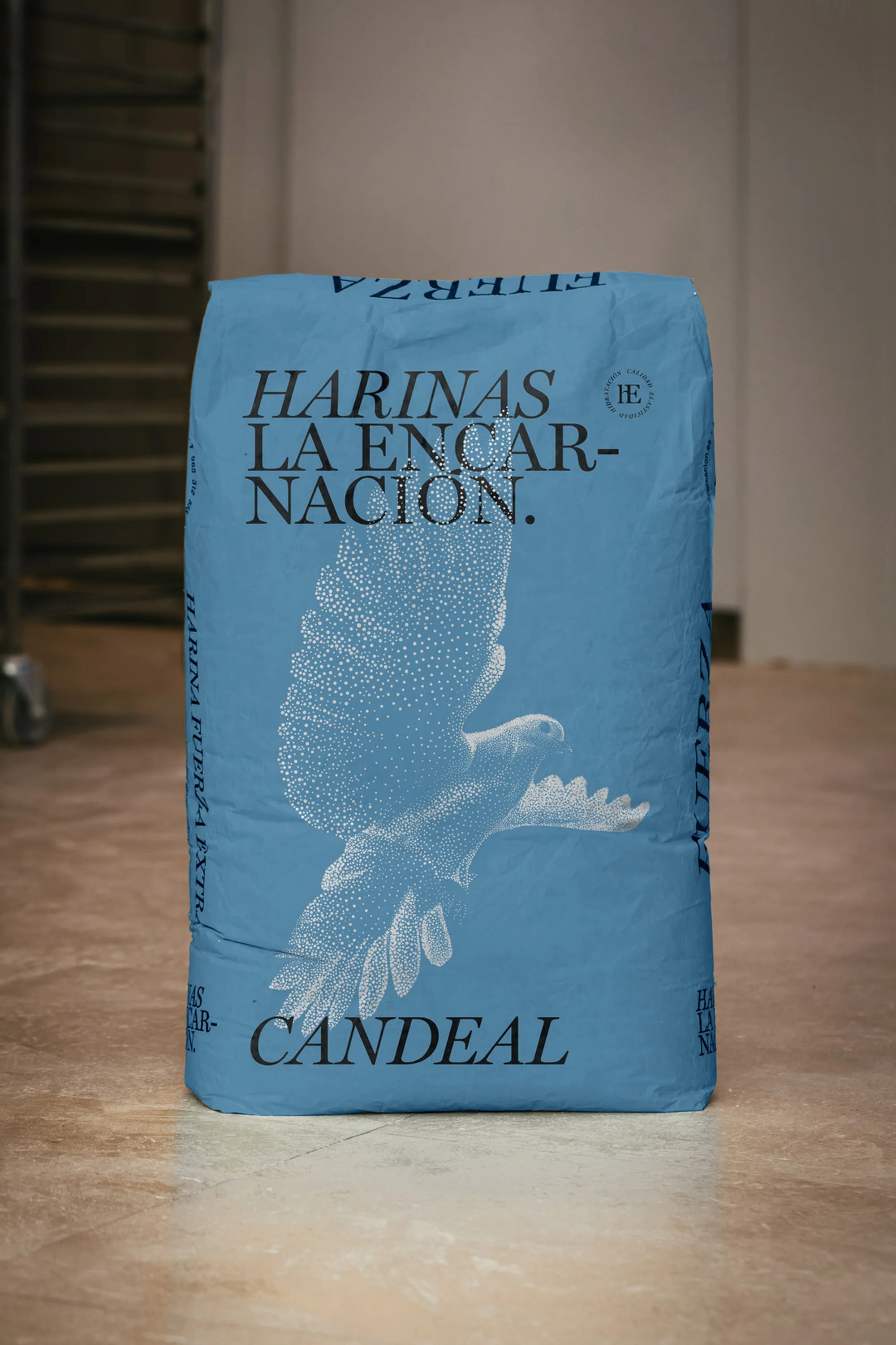 A bag of Harinas La Encarnacion Candeal brand flour stands upright, featuring a blue background, black text, and a white eagle graphic.