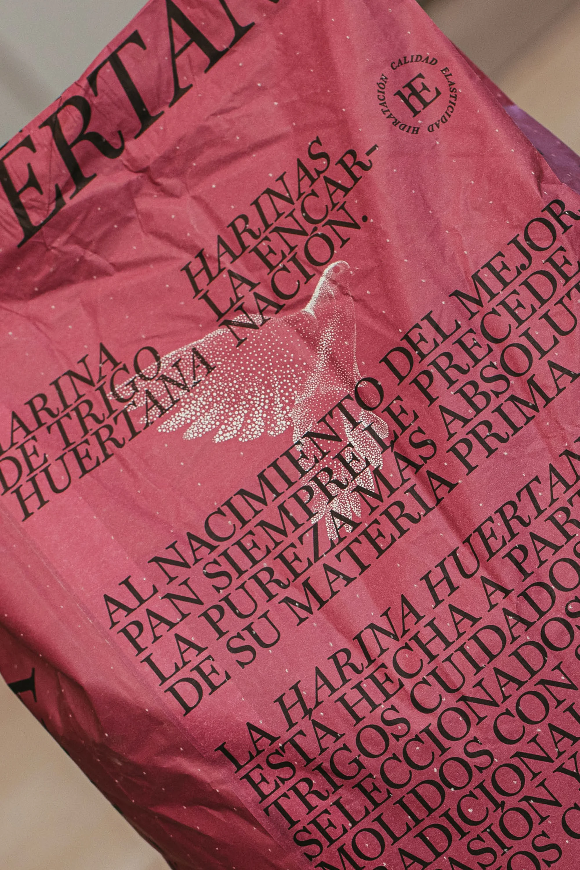 Close-up of red packaging with black Spanish text featuring the words 'Harina de Trigo Huertana' and an illustration of a white dove.