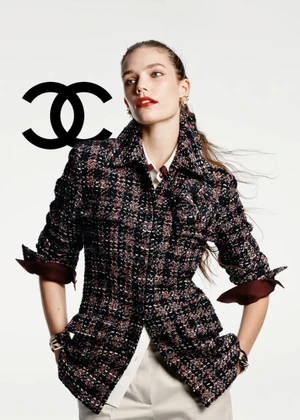 Model wearing a patterned tweed jacket and light trousers against a plain white background with the Chanel logo