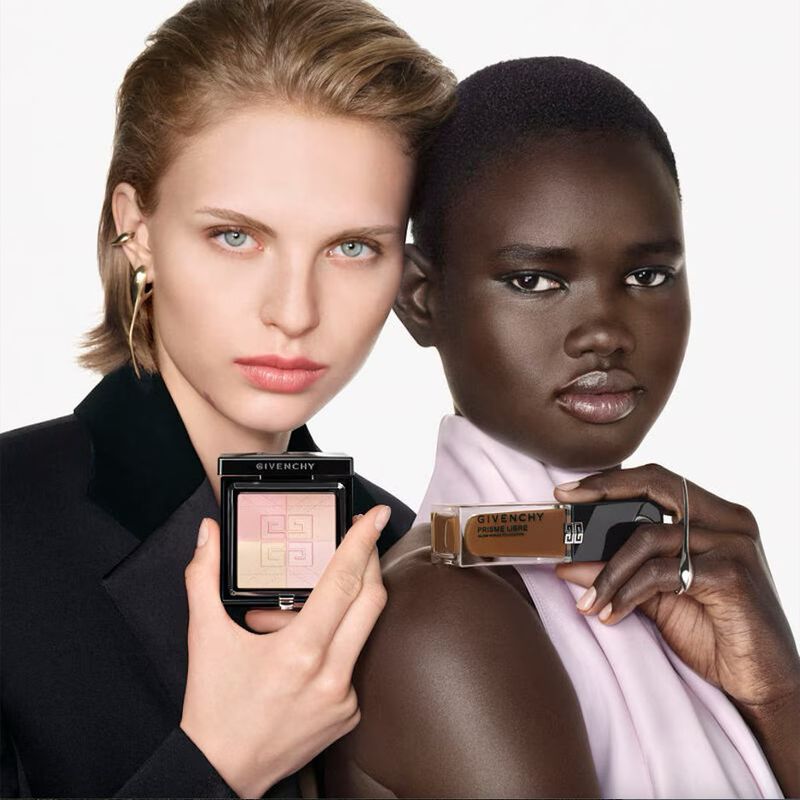 Two fashion models, one fair-skinned and one dark-skinned, pose with Givenchy makeup in a studio shot for a beauty ad campaign.