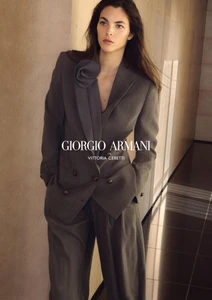 Model Vittoria Ceretti wearing a grey pantsuit in a hallway for the Giorgio Armani S/S 2026 campaign