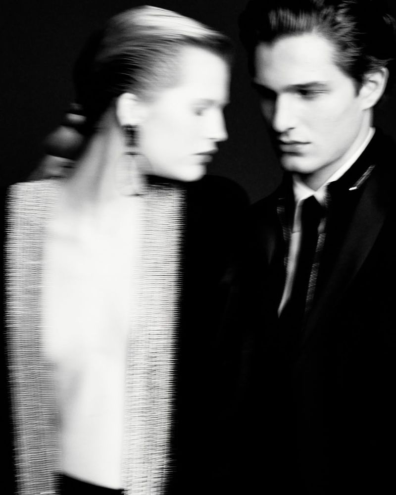 Elegant black and white fashion shot of a couple. The woman is wearing a light-colored beaded top and the man a black tuxedo.