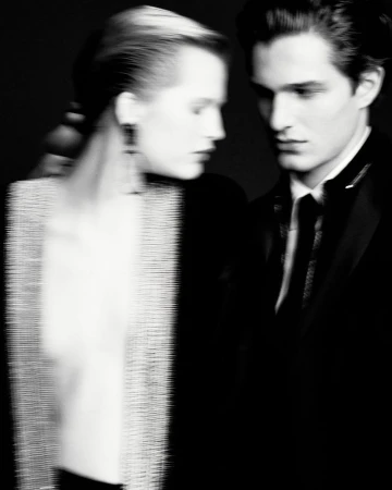 Elegant black and white fashion shot of a couple. The woman is wearing a light-colored beaded top and the man a black tuxedo.