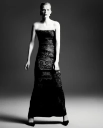 Model in strapless black lace gown standing against a neutral studio backdrop for Giorgio Armani FW25 collection