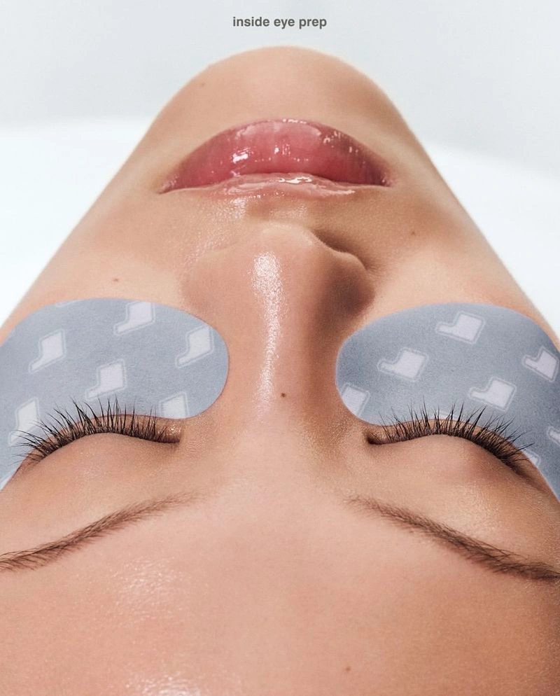 Close-up portrait of a model wearing grey eye masks under closed eyes for the rhode Skin peptide eye prep campaign.