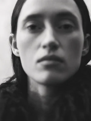 Close-up portrait of a woman with dark hair against a plain background