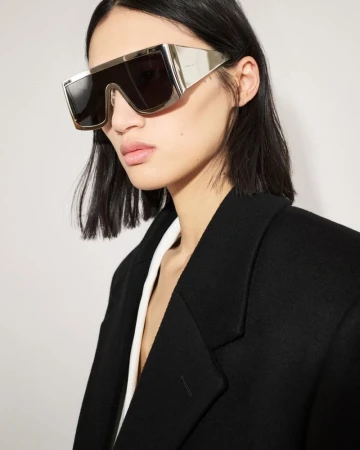 Model wearing oversized metallic sunglasses and a black blazer against a white background for the Givenchy campaign.