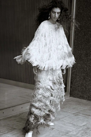 Model Sun Mizrahi wearing a fringed white outfit in a monochrome fashion editorial by Sonia Szóstak for Financial Times HTSI Magazine.