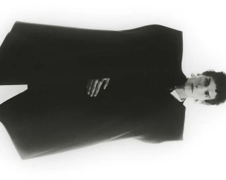 Model Leandro da Silva wearing a dark structured coat against a bright white background for Numero Netherlands.