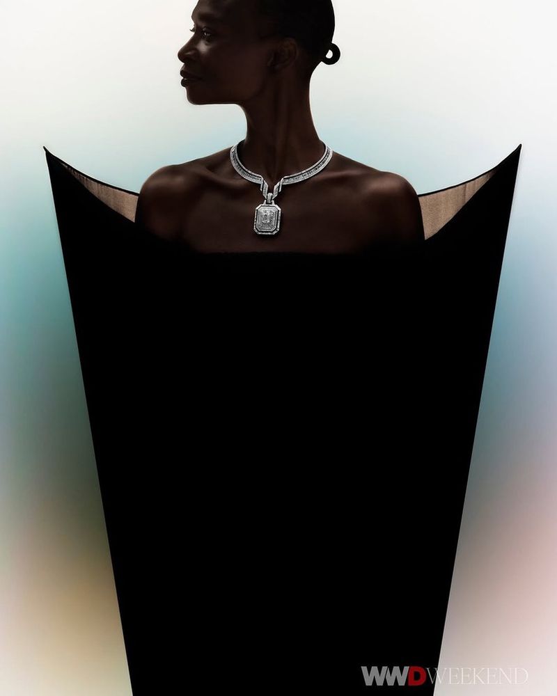 Dark-skinned woman in profile wearing a diamond necklace and black dress with a light gradient background, and the WWD Weekend logo.